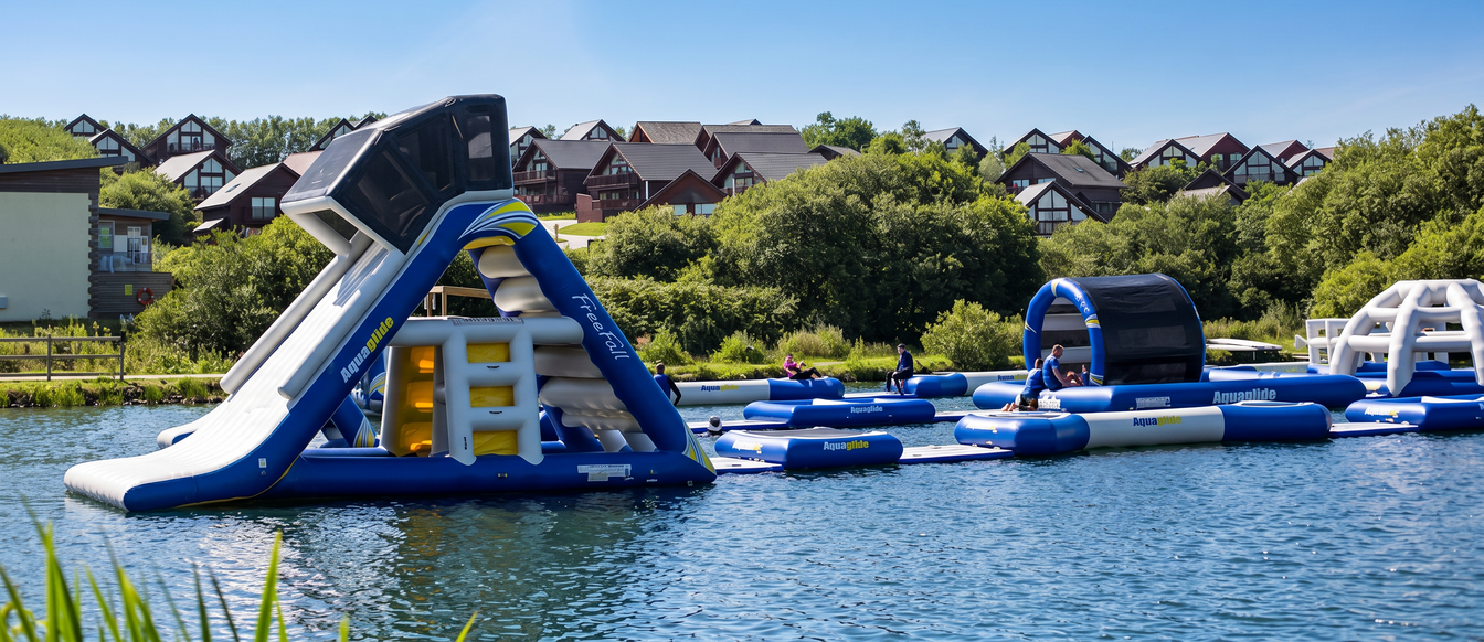 Inflatable aqua park on the lake at Retallack Resort in Cornwall with lodges in the background