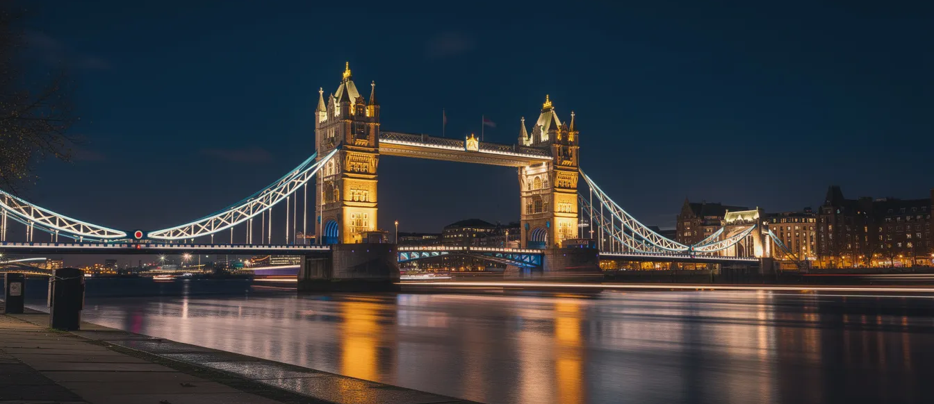 The image shows the iconic Tower Bridge illuminated at night, casting stunning reflections on the River Thames below. This breathtaking view highlights London's rich history and architecture, making it a perfect backdrop for visitors exploring nearby attractions like the Tower of London.
